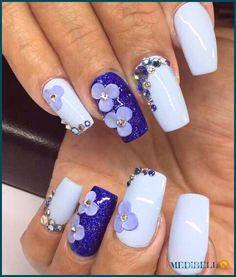 Tonos de diseño de uñas acrílicas azules con acentos florales.